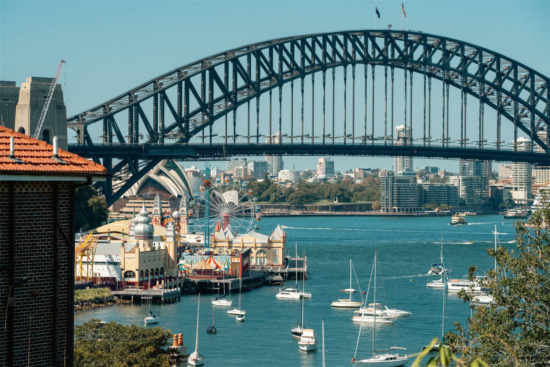 The Sydney Harbour Bridge arching over the harbor with the Opera House and sailboats below