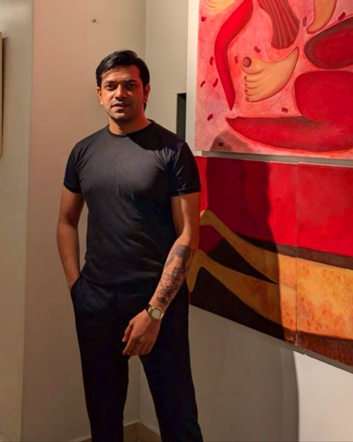 Nitin Kumar, a School Decide student, standing in a black t-shirt beside colorful gallery artwork