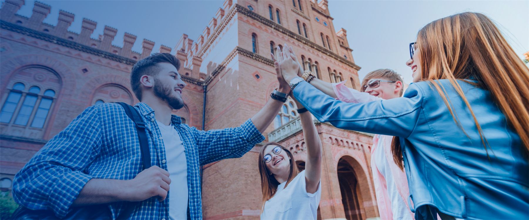 Students high-fiving in front of a historic university building