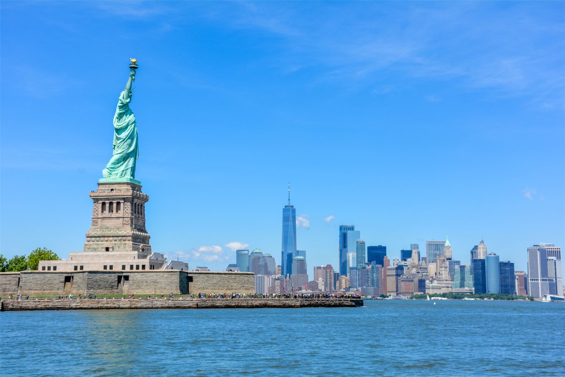 The Statue of Liberty with the Manhattan skyline behind it on a clear day